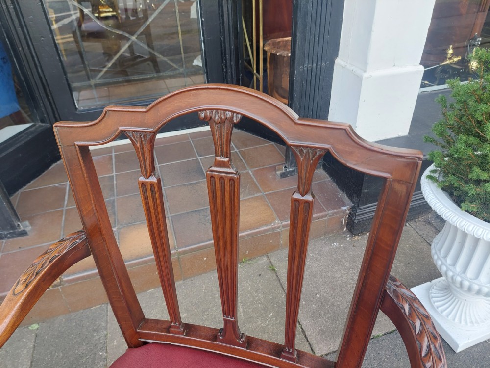 A George III mahogany carver chair featuring vertical fluted back slats, curved armrests, and a red leather seat secured with brass studding. View II