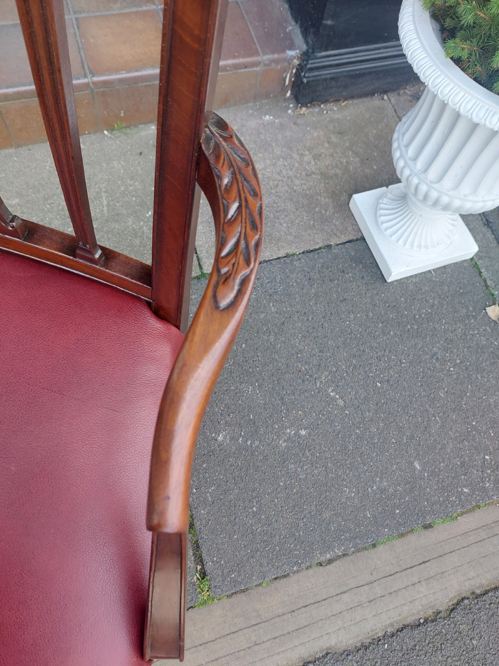 A George III mahogany carver chair featuring vertical fluted back slats, curved armrests, and a red leather seat secured with brass studding. View III