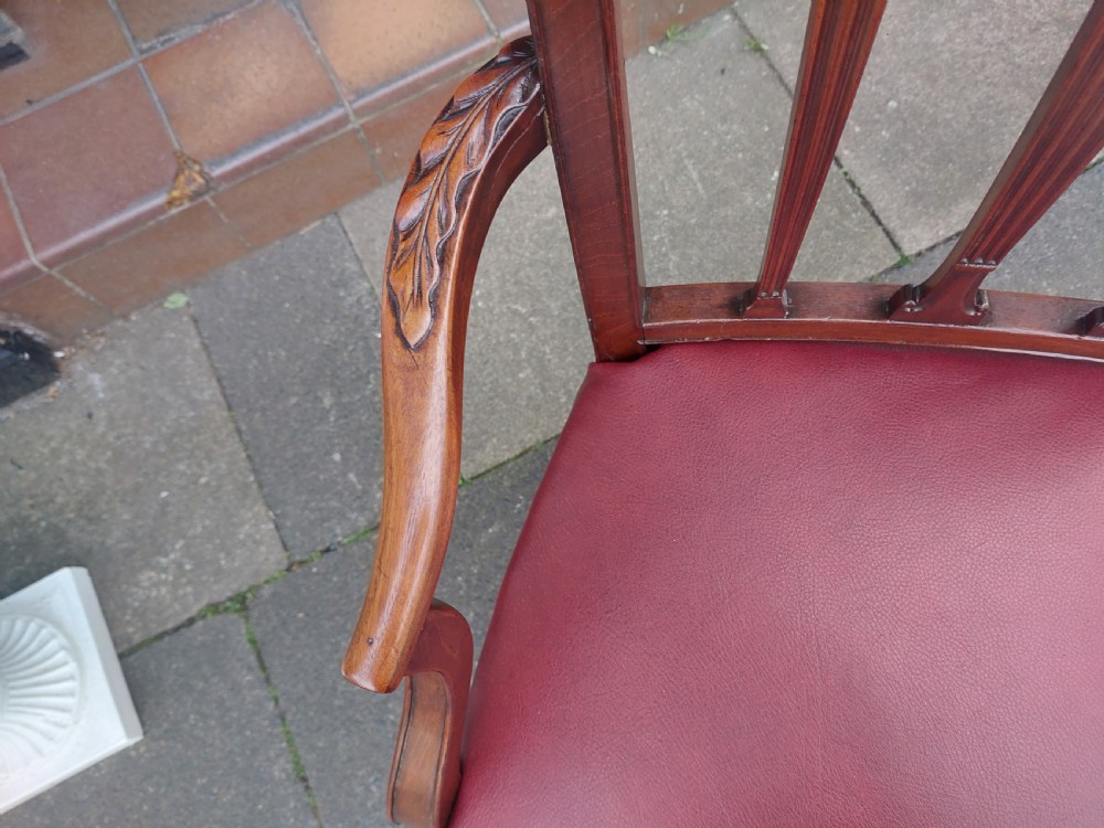 A George III mahogany carver chair featuring vertical fluted back slats, curved armrests, and a red leather seat secured with brass studding. View IV