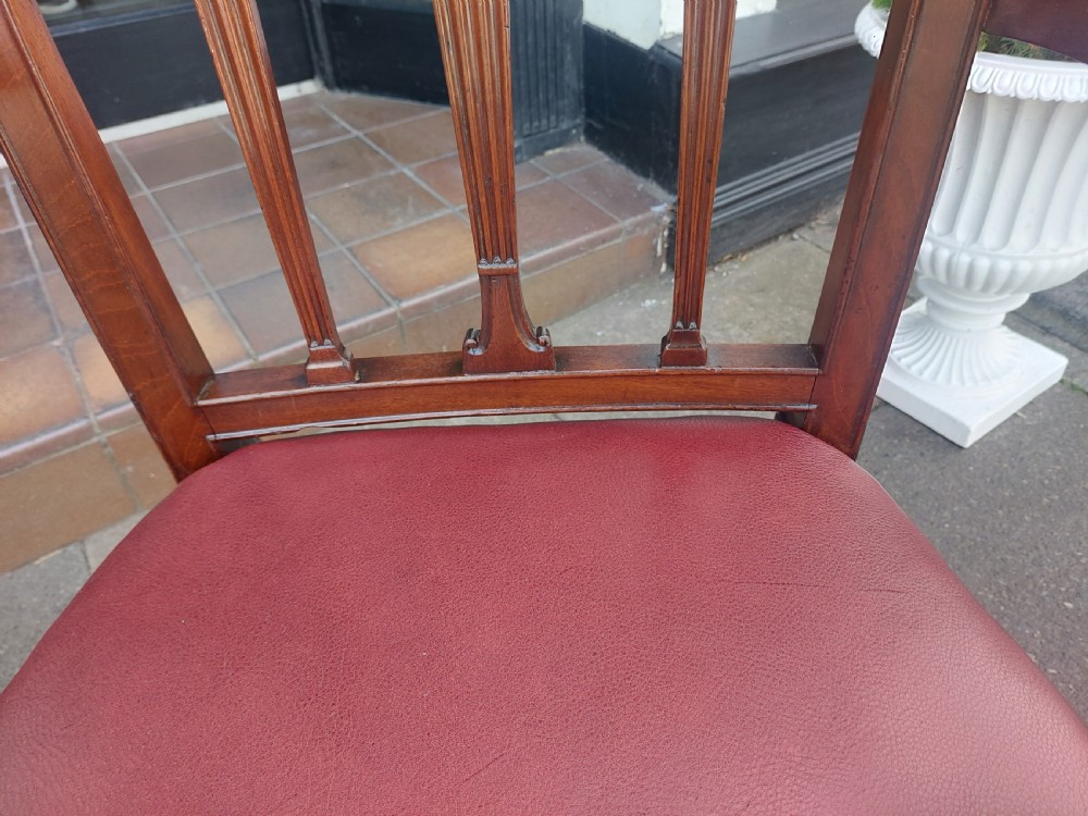 A George III mahogany carver chair featuring vertical fluted back slats, curved armrests, and a red leather seat secured with brass studding. View VI