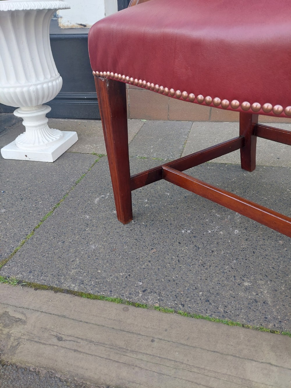 A George III mahogany carver chair featuring vertical fluted back slats, curved armrests, and a red leather seat secured with brass studding. View VII