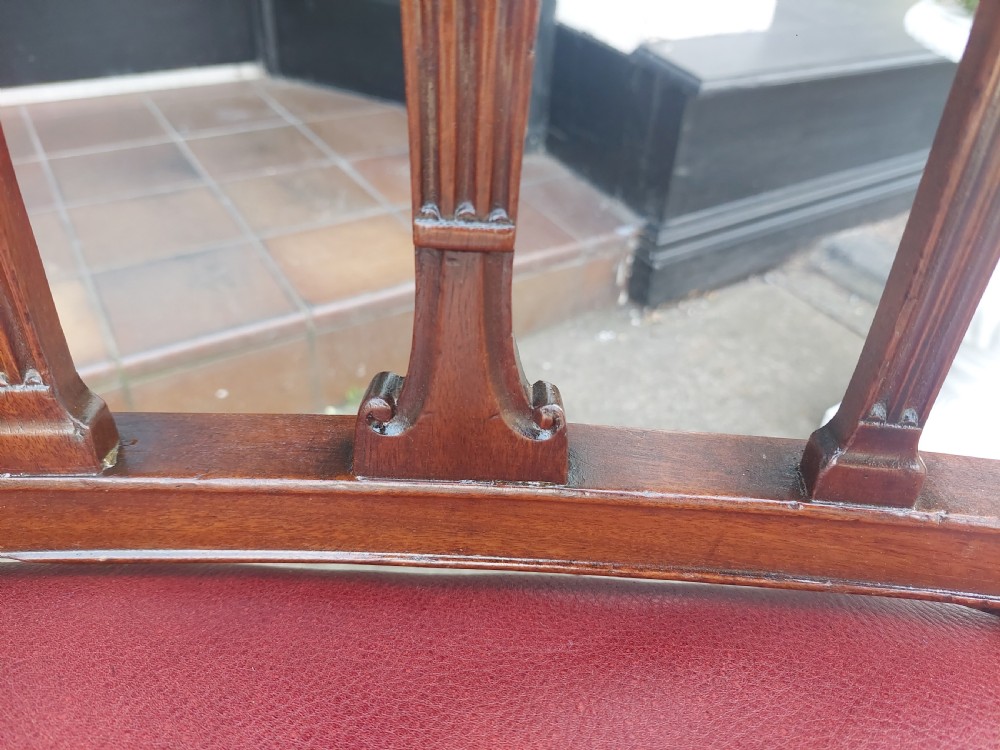 A George III mahogany carver chair featuring vertical fluted back slats, curved armrests, and a red leather seat secured with brass studding. View IX
