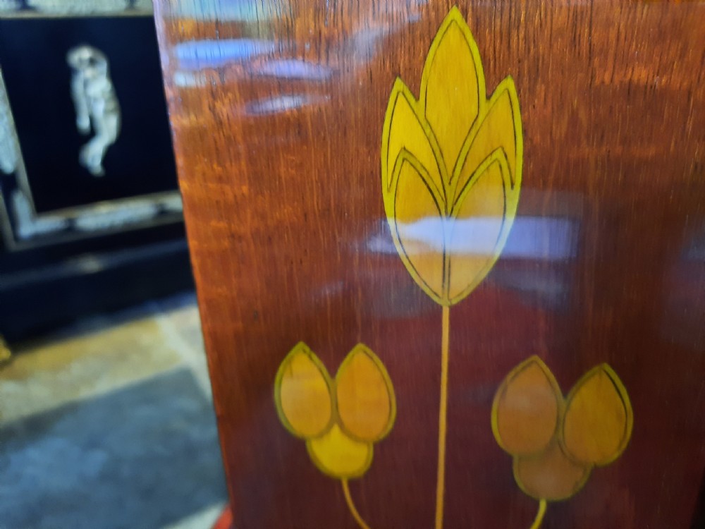 An Art Nouveau mahogany revolving bookcase featuring floral marquetry inlay on the side panel and two open tier shelves filled with leather-bound books. View VI