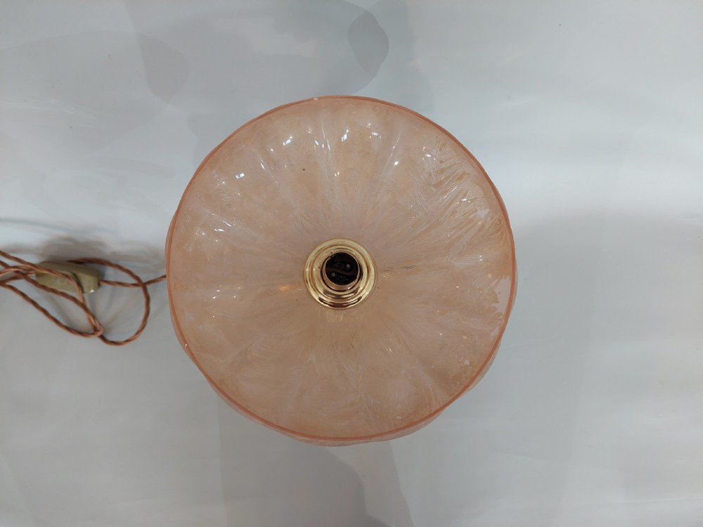 An Art Deco polished brass table lamp featuring a stylized female figure within a crescent frame supporting a pink frosted glass bowl shade. View IV