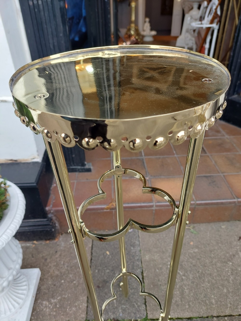 A pair of slender early 20th-century polished brass jardiniere stands with beaded circular tops, trefoil stretchers, and splayed legs. View III
