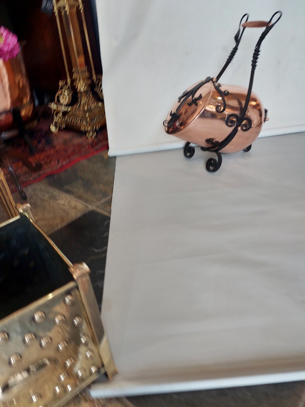 A hand-hammered copper coal receiver supported by a black wrought iron frame with scroll feet and an elevated handle. View II