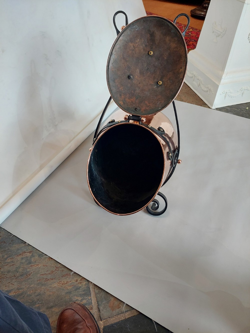 A hand-hammered copper coal receiver supported by a black wrought iron frame with scroll feet and an elevated handle. View XIII