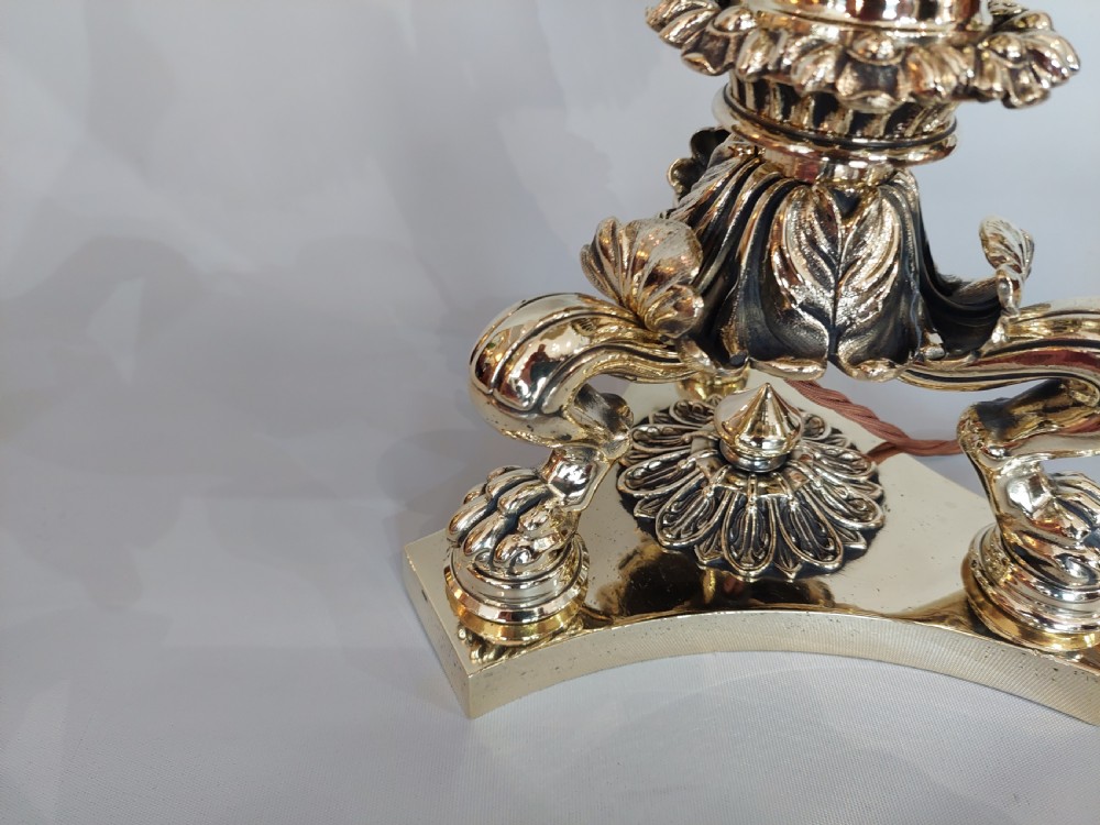 A Victorian brass table lamp featuring a columned base with acanthus leaf moulding and a cream fabric lampshade trimmed with burgundy fringe. View II