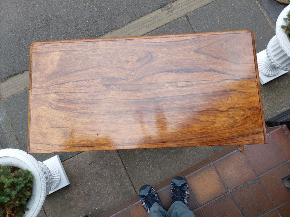A William IV rosewood card table featuring a rectangular swivel top resting on a tapered column pedestal and a concave quadform plinth base with scroll feet. View II