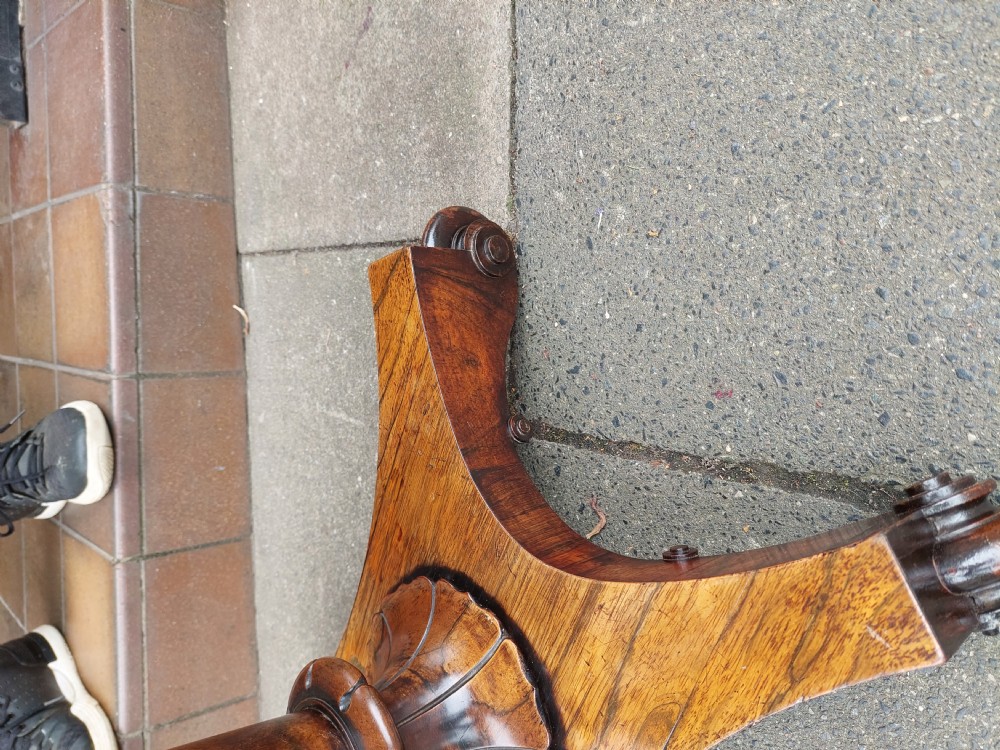 A William IV rosewood card table featuring a rectangular swivel top resting on a tapered column pedestal and a concave quadform plinth base with scroll feet. View V