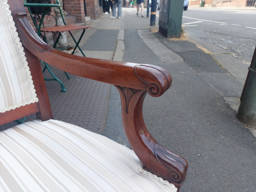 A pair of late 19th-century carved mahogany open armchairs upholstered in cream striped fabric with gimp braid trim. View II