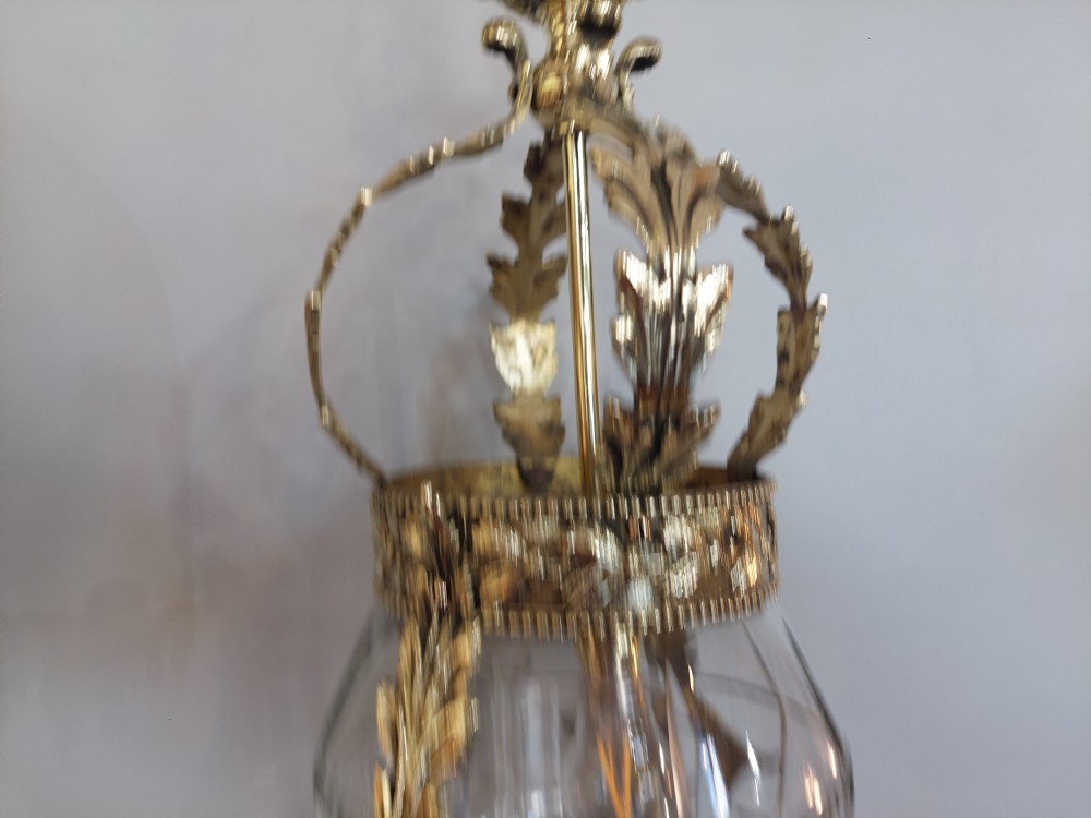 An early 20th-century brass hanging lantern featuring a cut glass shade, ornate leaf scrollwork framing, and a central suspension chain. View III