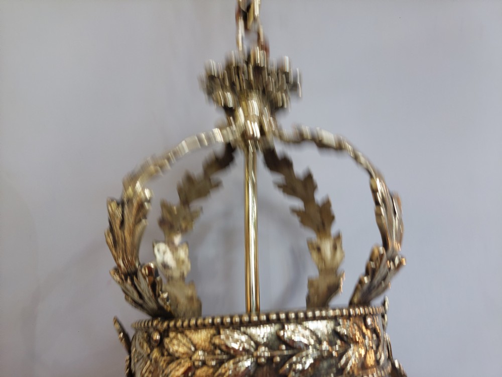 An early 20th-century brass hanging lantern featuring a cut glass shade, ornate leaf scrollwork framing, and a central suspension chain. View VI