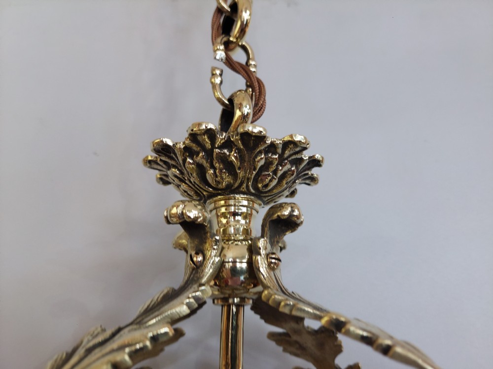 An early 20th-century brass hanging lantern featuring a cut glass shade, ornate leaf scrollwork framing, and a central suspension chain. View VII