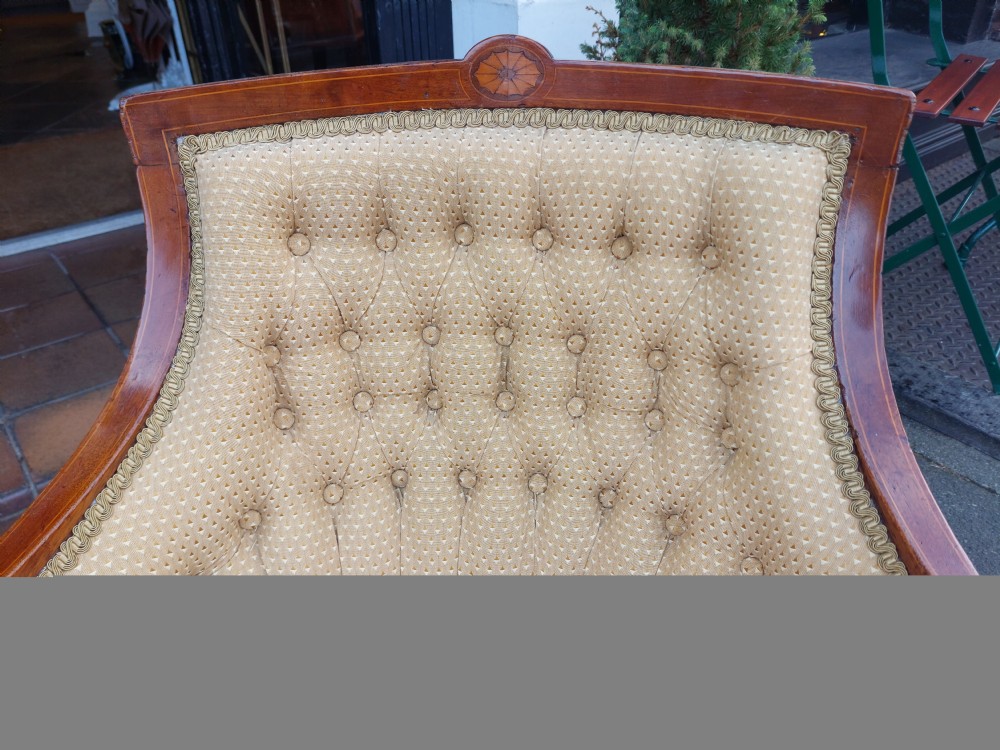 An Edwardian childs armchair with mahogany frame, marquetry patera inlay, deep-buttoned yellow pattern upholstery, and tapered square front legs. View IV