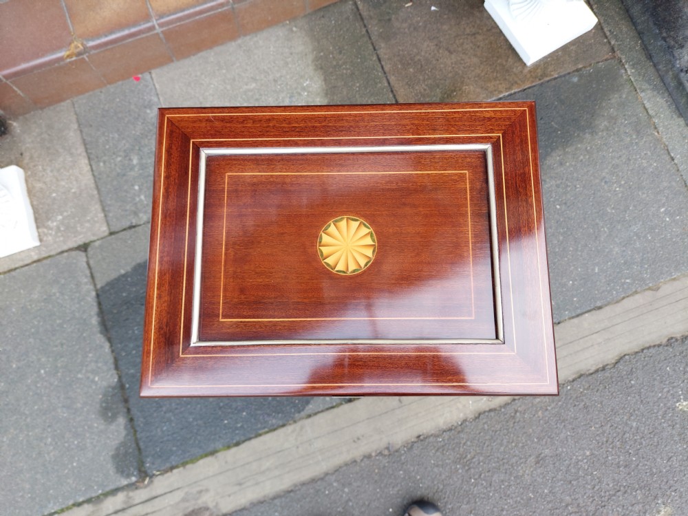 An early twentieth-century mahogany gentlemans vanity table featuring a hinged top mirror and side compartments displaying glass bottles and grooming accessories. View V