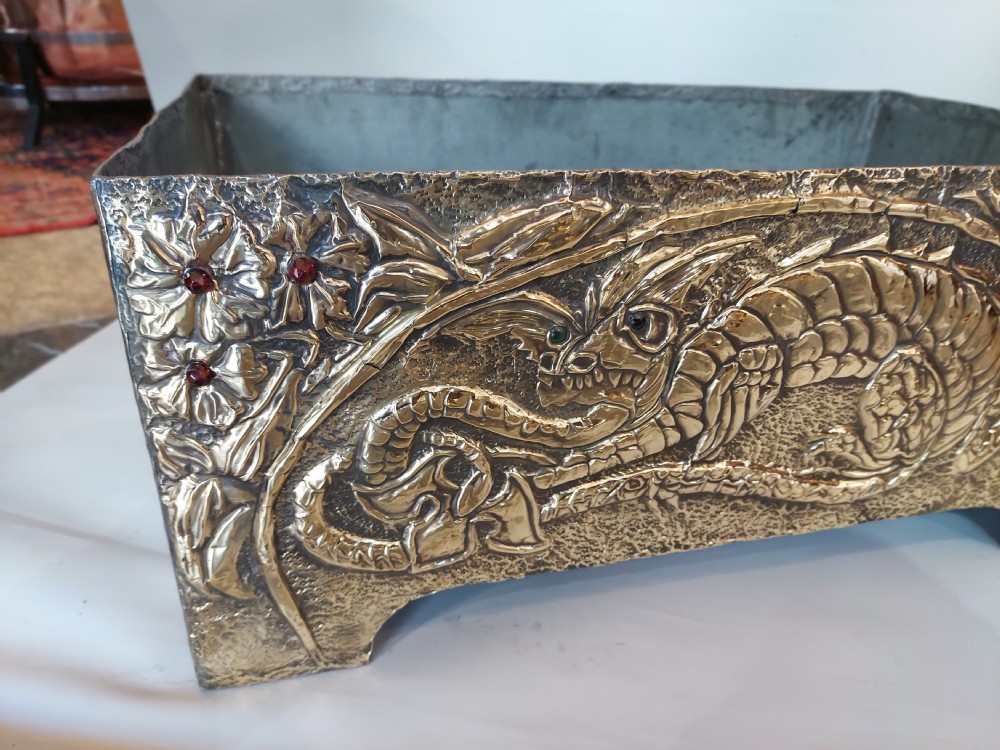 A rectangular brass trough planter featuring zinc lining and hand-chased relief work of a dragon among floral branches inset with red glass cabochons. View II