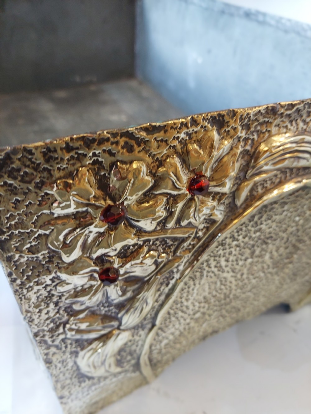 A rectangular brass trough planter featuring zinc lining and hand-chased relief work of a dragon among floral branches inset with red glass cabochons. View V
