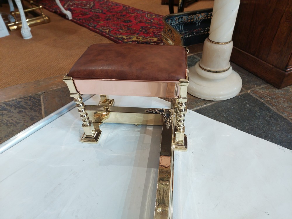 A Victorian brass and copper club fender featuring two padded brown leather corner seats raised on turned brass supports with decorative metal frieze detail. View VIII