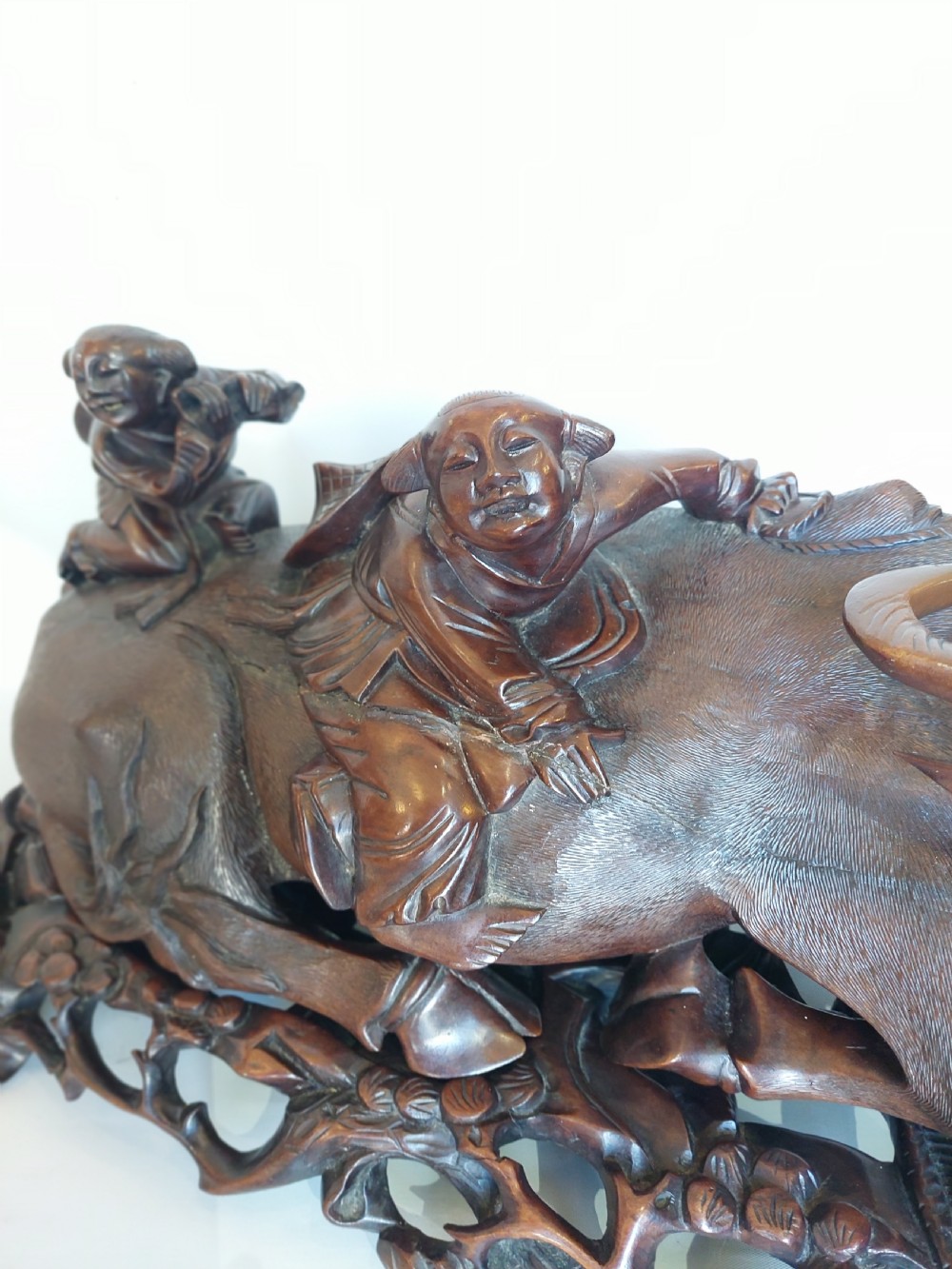 A 19th-century Chinese carved root wood sculpture depicting two boys riding a reclining water buffalo set upon a carved pierced base. View III