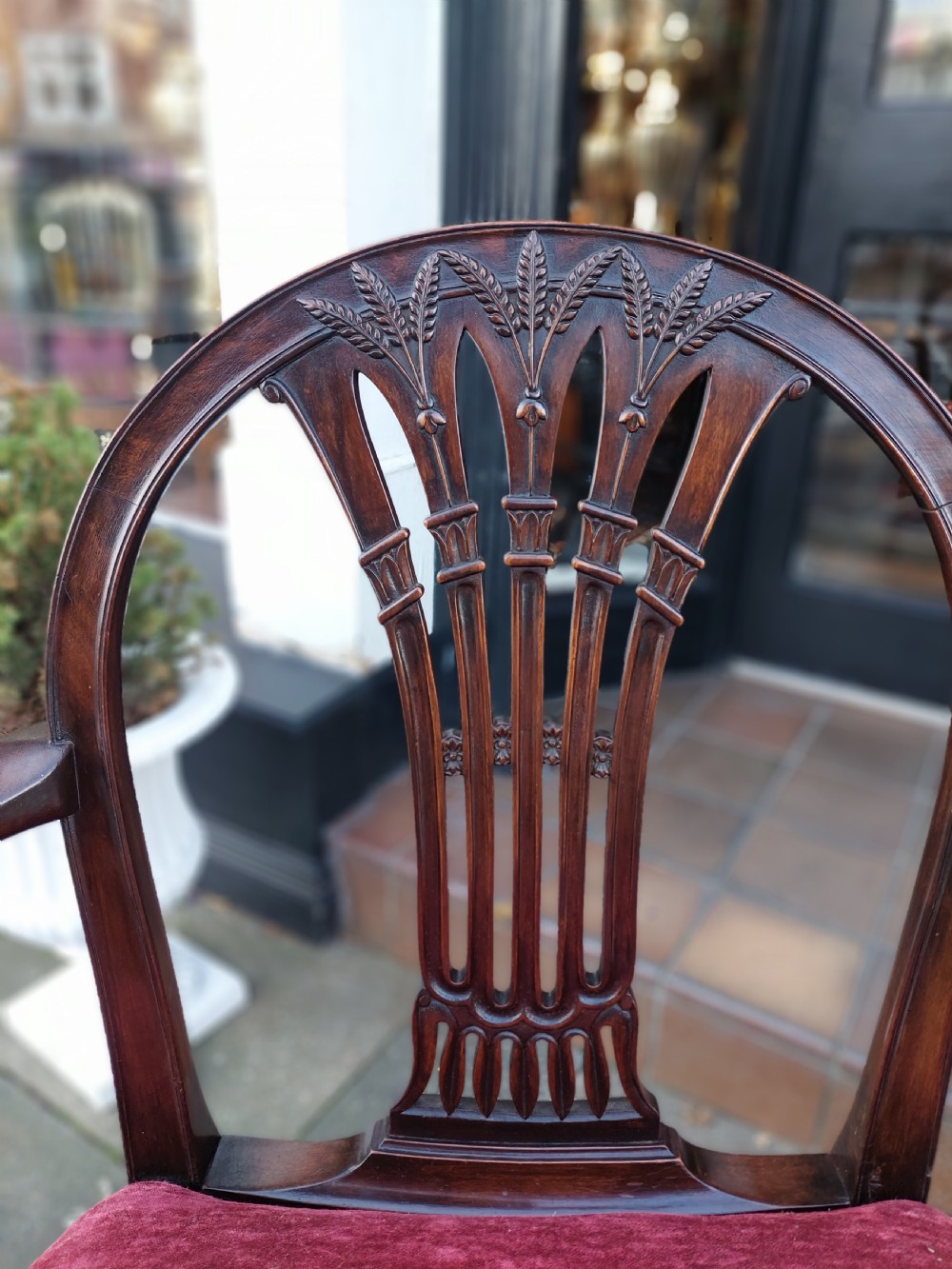 A late 19th-century Hepplewhite style mahogany armchair featuring a carved wheat sheaf oval backrest, curved arms, and a red velvet upholstered seat. View III