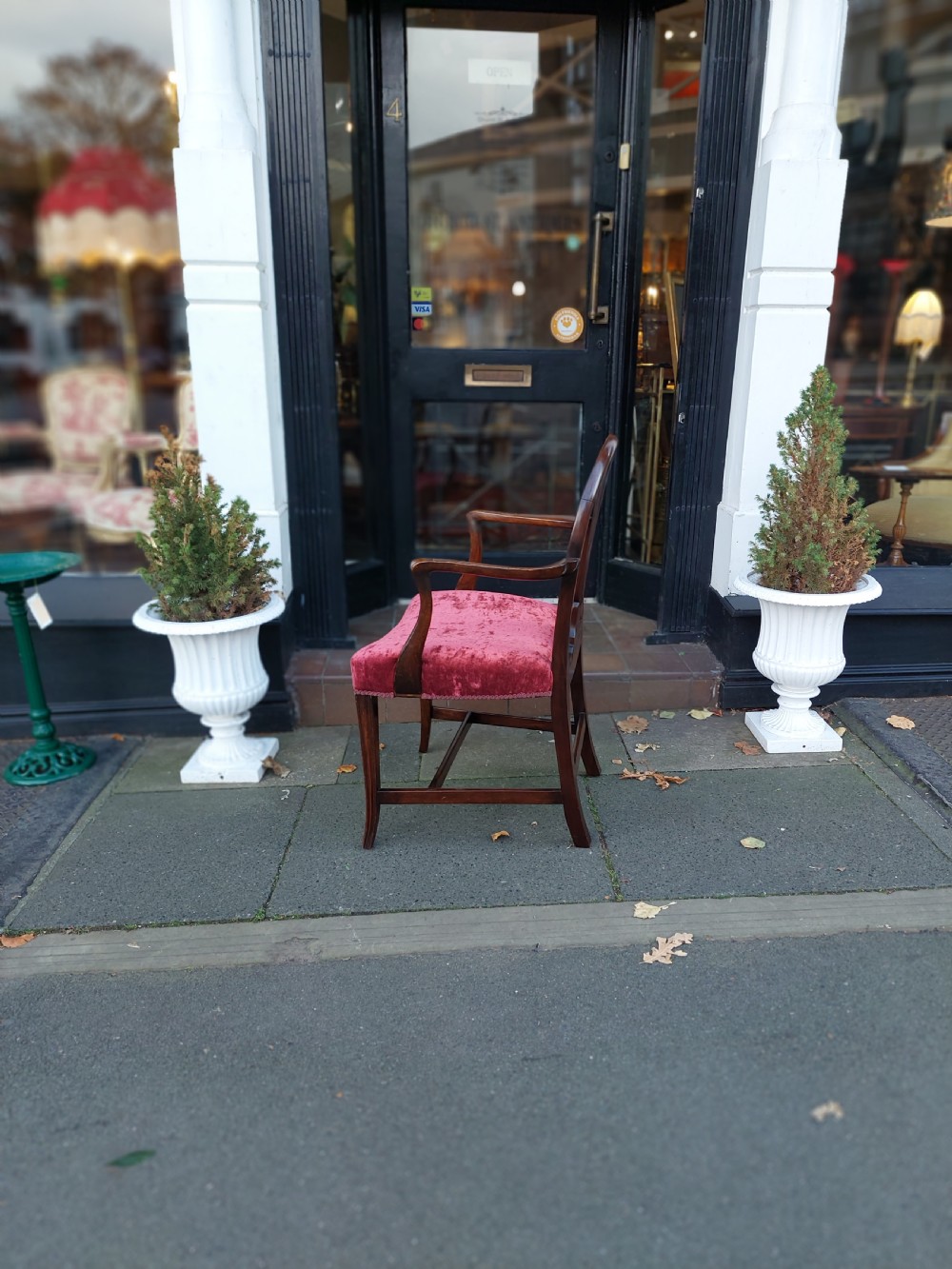 A late 19th-century Hepplewhite style mahogany armchair featuring a carved wheat sheaf oval backrest, curved arms, and a red velvet upholstered seat. View X