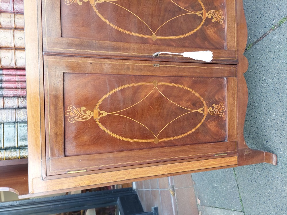 An Edwardian mahogany waterfall bookcase featuring two open graduated shelves above a two-door cabinet with oval satinwood marquetry inlay. View V