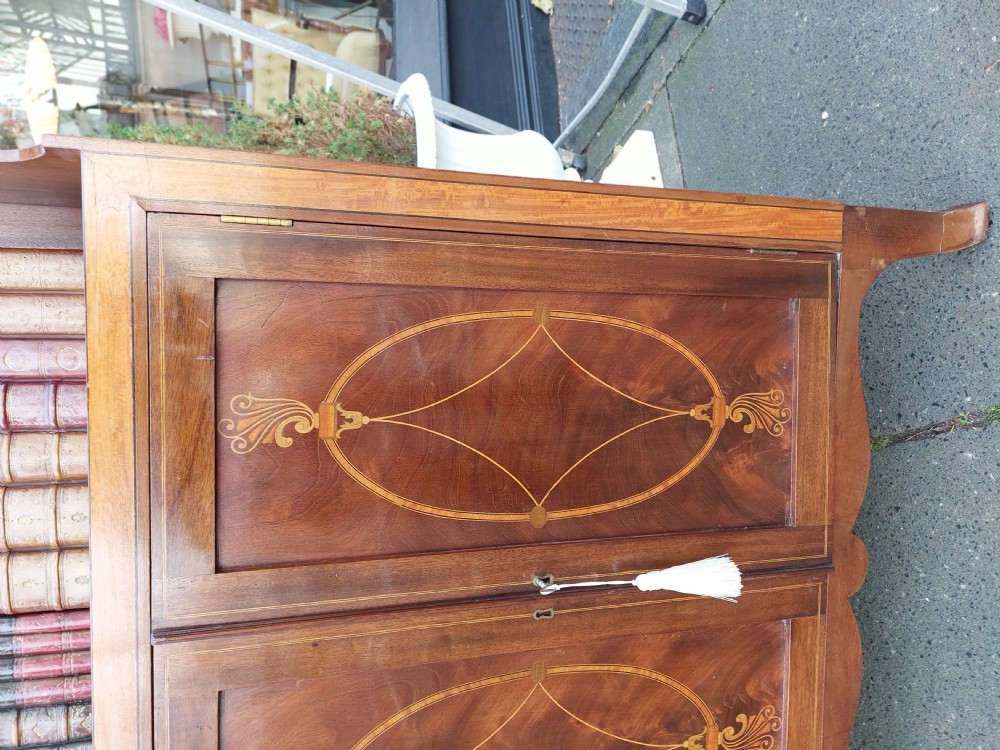 An Edwardian mahogany waterfall bookcase featuring two open graduated shelves above a two-door cabinet with oval satinwood marquetry inlay. View VI