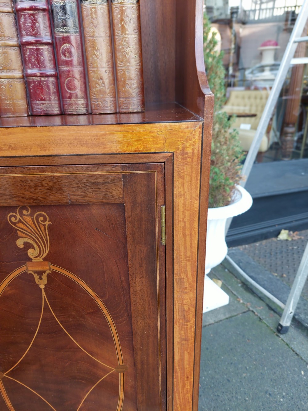 An Edwardian mahogany waterfall bookcase featuring two open graduated shelves above a two-door cabinet with oval satinwood marquetry inlay. View VIII