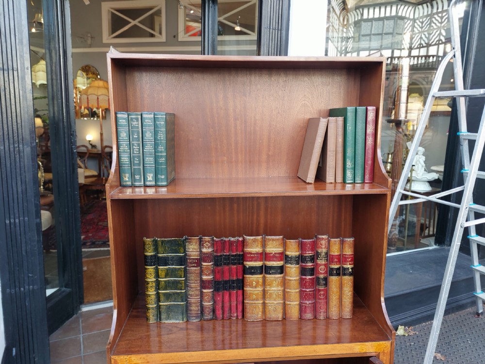 An Edwardian mahogany waterfall bookcase featuring two open graduated shelves above a two-door cabinet with oval satinwood marquetry inlay. View IX