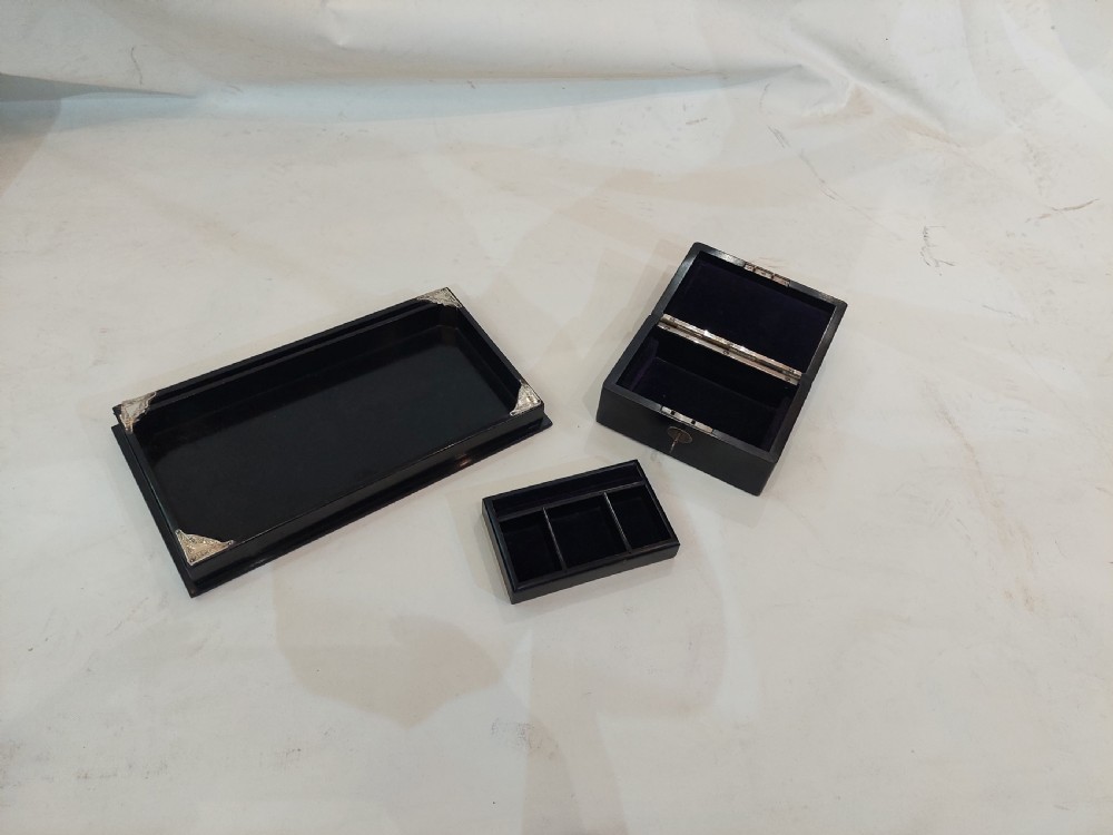 A rectangular black ebonised jewellery box with inlaid silver script alongside a matching tray featuring silver corner mounts. View II