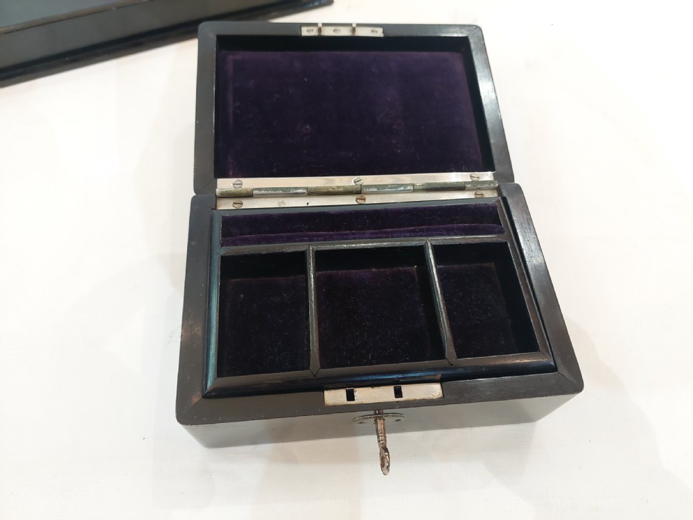A rectangular black ebonised jewellery box with inlaid silver script alongside a matching tray featuring silver corner mounts. View III