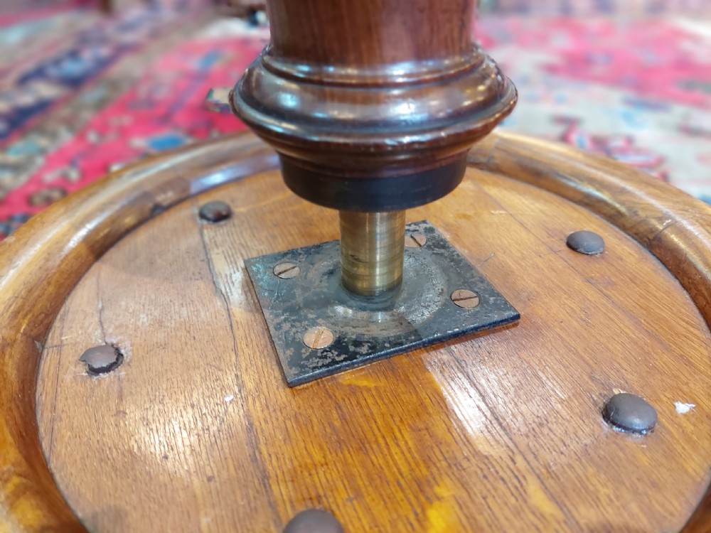 A Victorian dark walnut rise and fall piano stool with a circular cream upholstered seat and three carved cabriole legs with scroll feet. View V