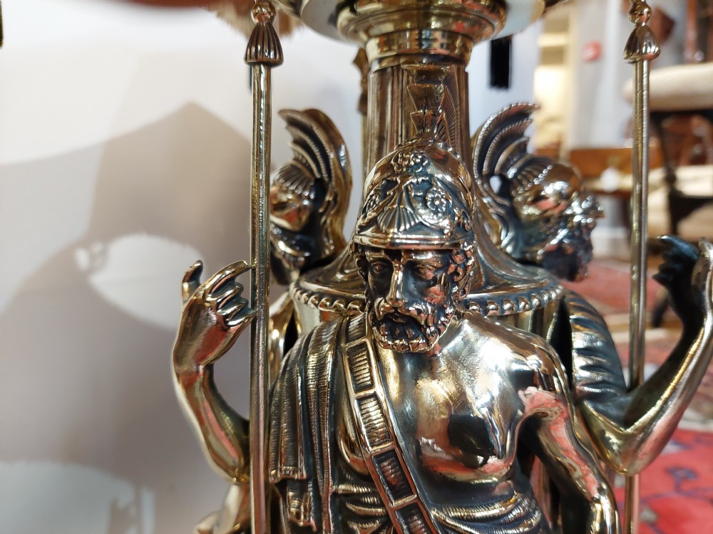 A late nineteenth-century brass table lamp featuring a sculptural base with classical soldier figures and a patterned hexagonal shade with long fringe. View II