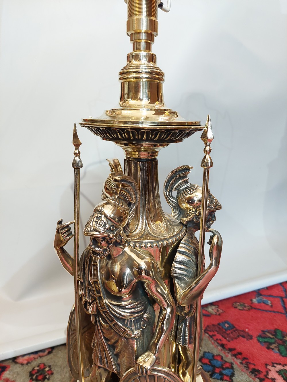A late nineteenth-century brass table lamp featuring a sculptural base with classical soldier figures and a patterned hexagonal shade with long fringe. View IV