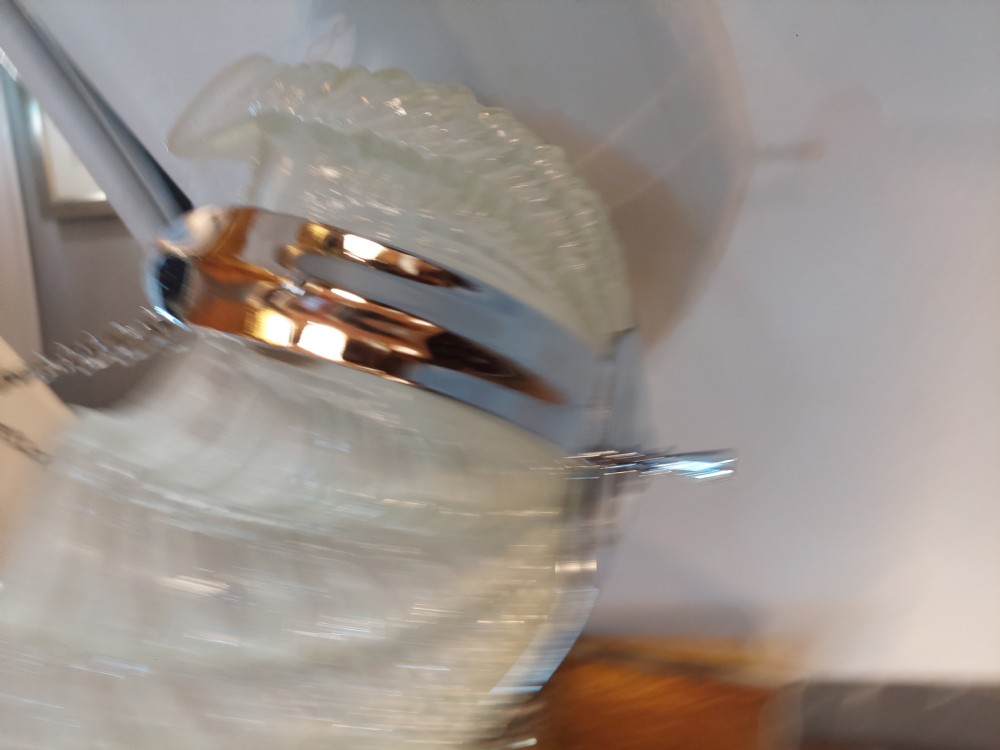 An Art Deco ceiling light fixture featuring three cream frosted glass clam shell shades held together by chrome brackets and suspended by three metal chains. View III