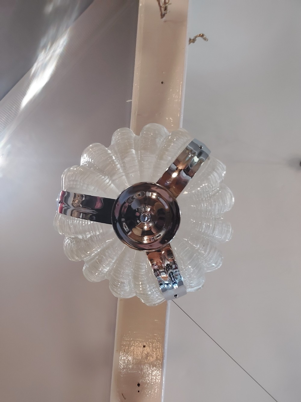 An Art Deco ceiling light fixture featuring three cream frosted glass clam shell shades held together by chrome brackets and suspended by three metal chains. View IV