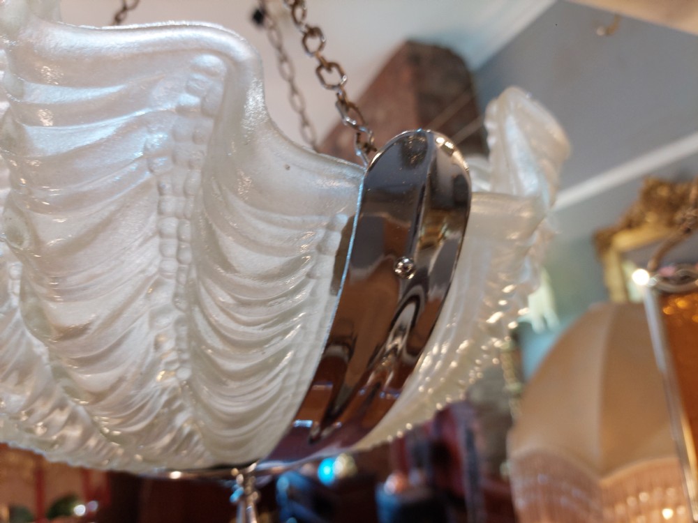 An Art Deco ceiling light fixture featuring three cream frosted glass clam shell shades held together by chrome brackets and suspended by three metal chains. View VI