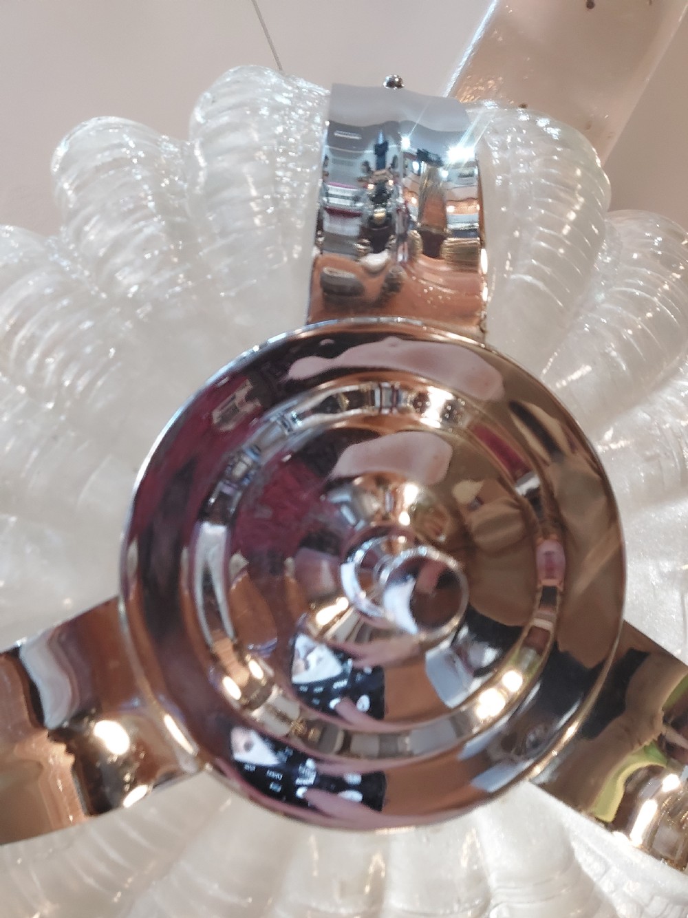 An Art Deco ceiling light fixture featuring three cream frosted glass clam shell shades held together by chrome brackets and suspended by three metal chains. View VII