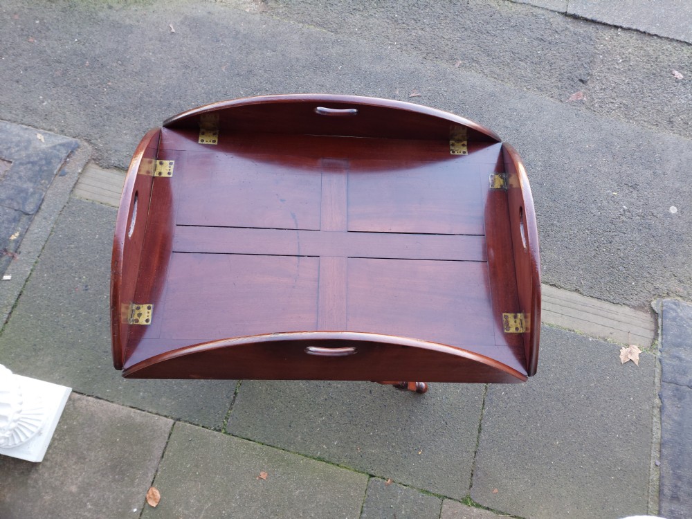 An early 19th-century Cuban mahogany oval butlers tray with hinged folding sides, brass fittings, and a turned X-frame stand. View V