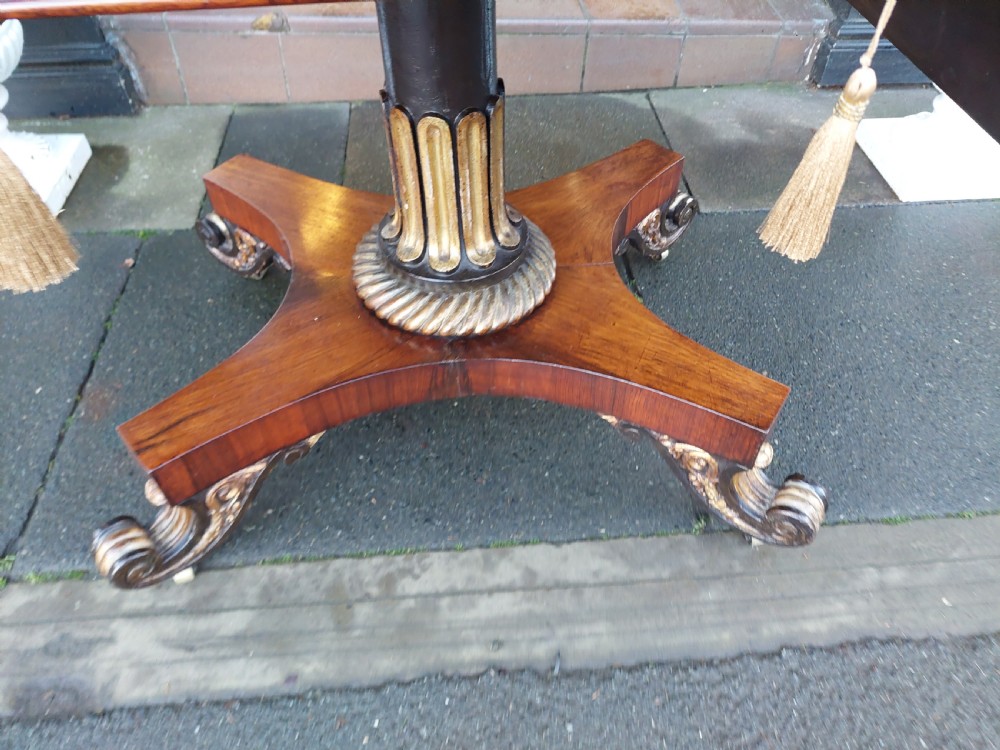 A Regency rosewood drop-leaf sofa table with twin inlaid drawers, a carved parcel gilt pedestal column, and a quadruped base ending in scroll feet. View VIII