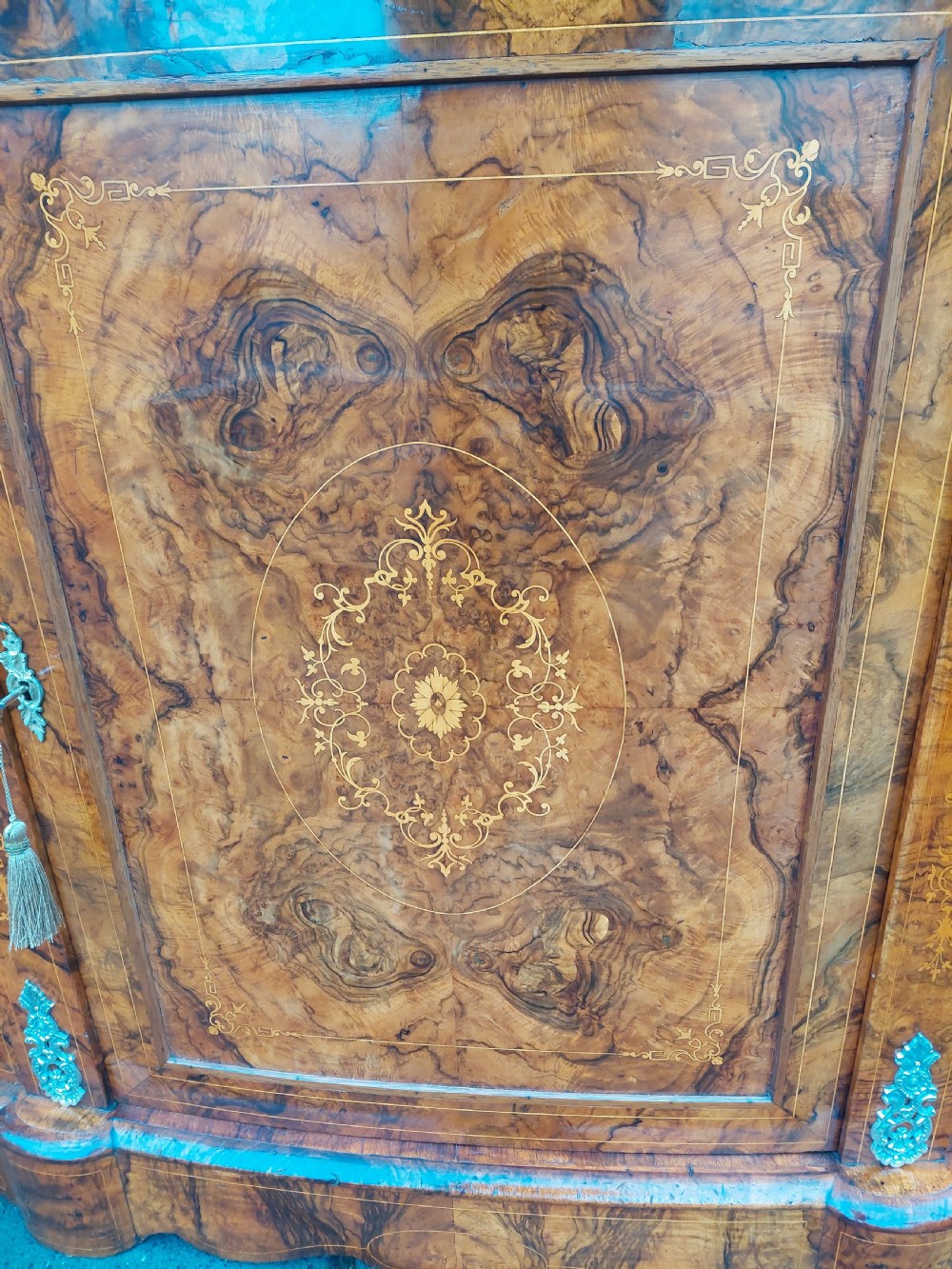 A Victorian burr walnut bow-fronted credenza featuring central inlaid wooden doors flanked by curved glazed display sections with ormolu mounts. View II