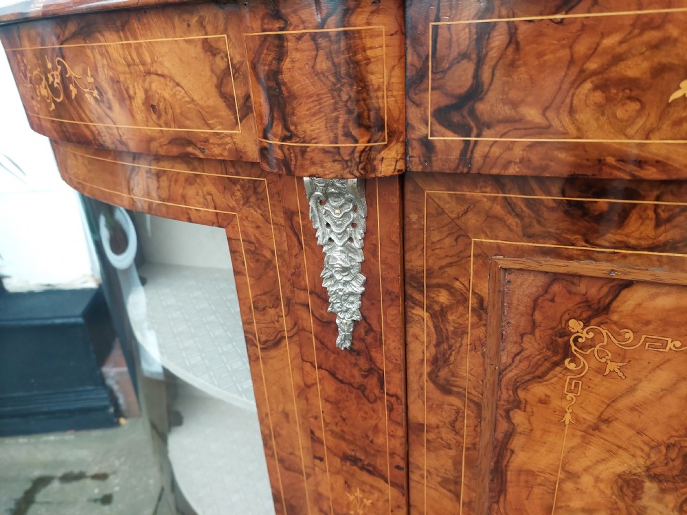 A Victorian burr walnut bow-fronted credenza featuring central inlaid wooden doors flanked by curved glazed display sections with ormolu mounts. View IV