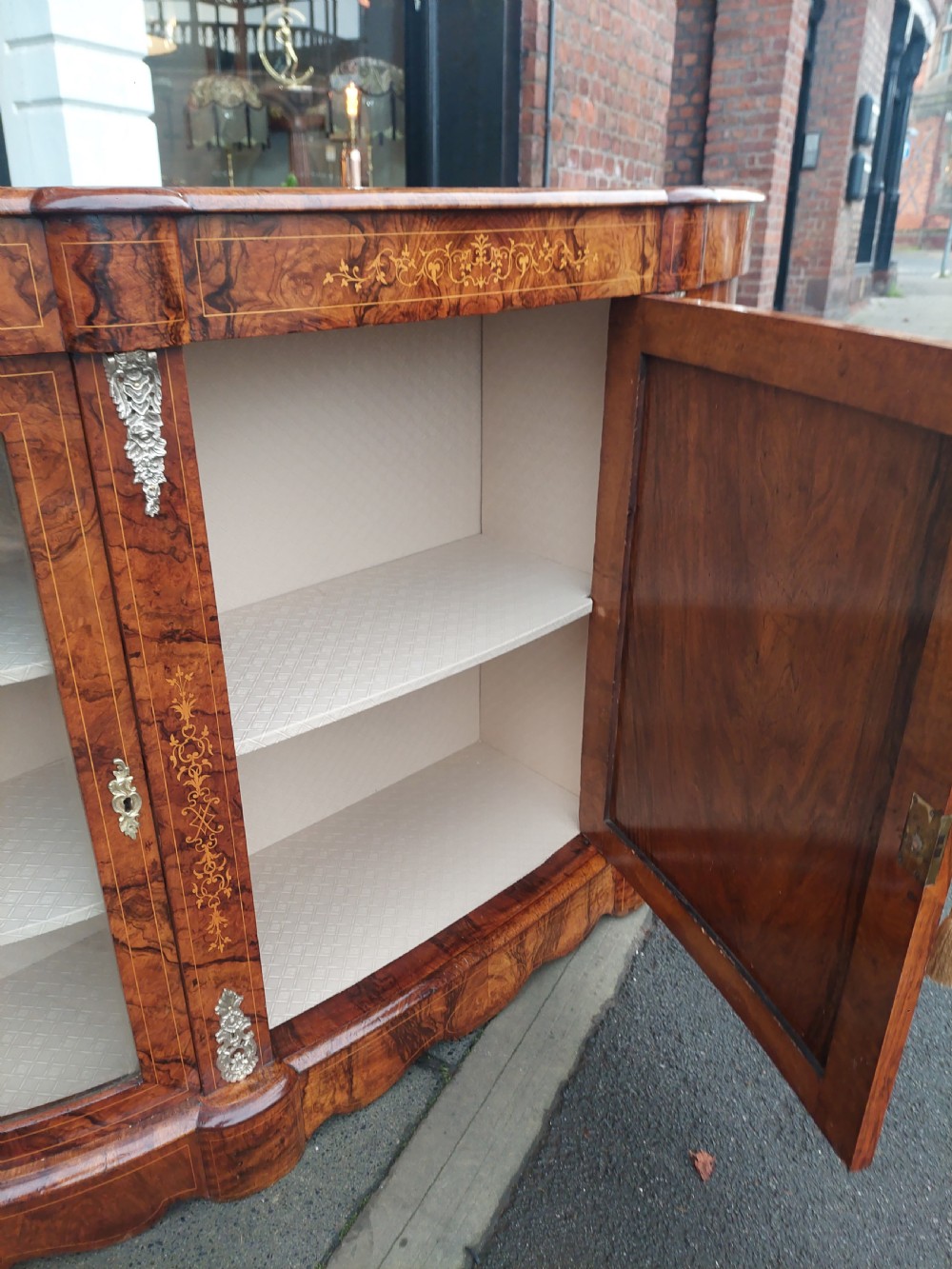 A Victorian burr walnut bow-fronted credenza featuring central inlaid wooden doors flanked by curved glazed display sections with ormolu mounts. View V