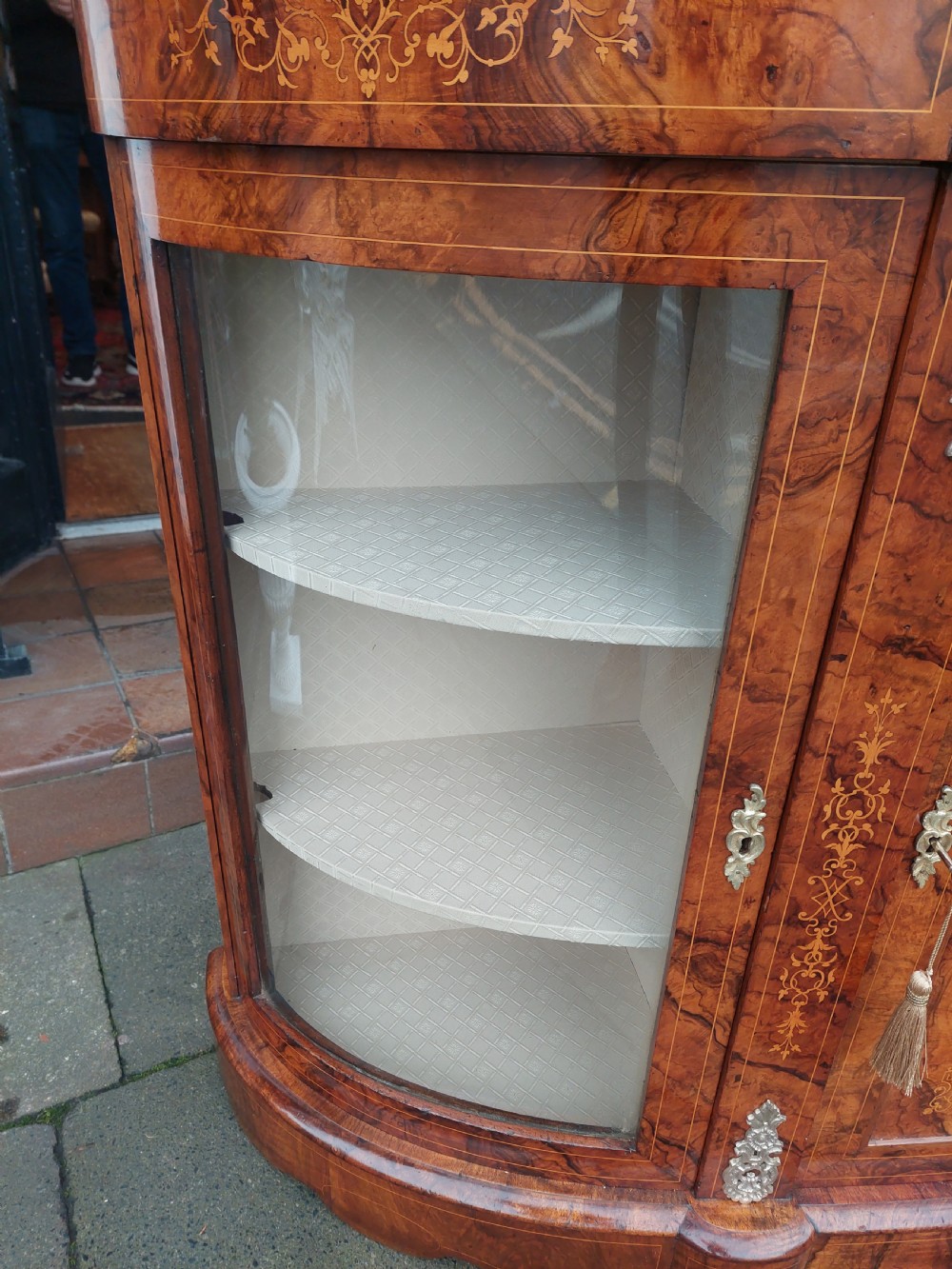 A Victorian burr walnut bow-fronted credenza featuring central inlaid wooden doors flanked by curved glazed display sections with ormolu mounts. View VI