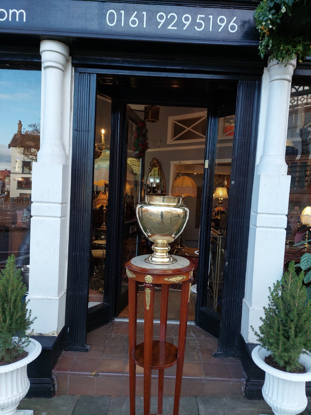 A polished Victorian brass planter featuring a rounded urn-shaped body resting on a stepped pedestal foot. View V