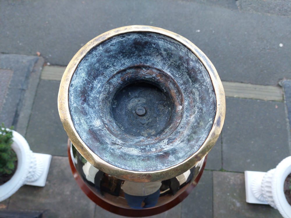 A polished Victorian brass planter featuring a rounded urn-shaped body resting on a stepped pedestal foot. View VII