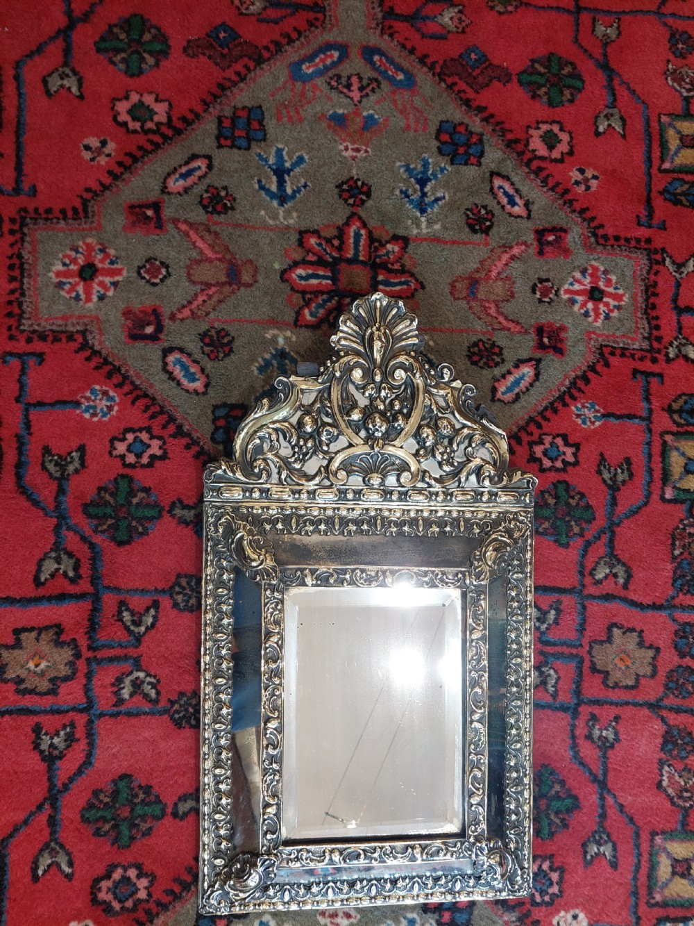 An early nineteenth-century Dutch style wall mirror featuring embossed repousse brass metalwork and a decorated crest over a central glass plate. View III