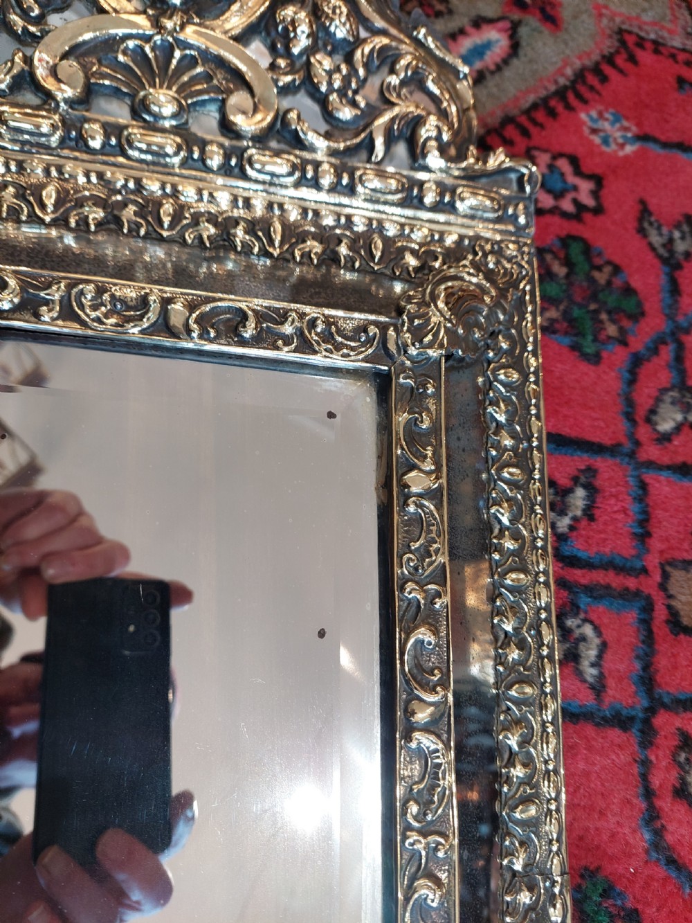 An early nineteenth-century Dutch style wall mirror featuring embossed repousse brass metalwork and a decorated crest over a central glass plate. View VII