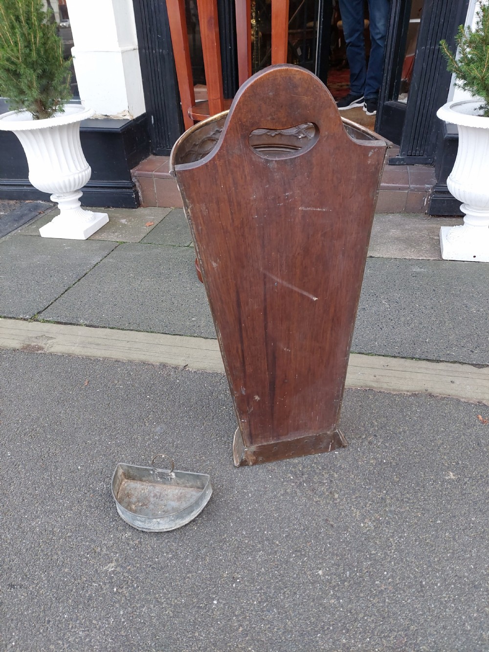 A polished Edwardian brass half-moon stick stand featuring embossed decorative borders and a dark wooden carrying handle. View XII